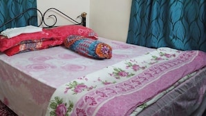 A bed with a floral bedspread, a rolled-up blanket, and pillows.