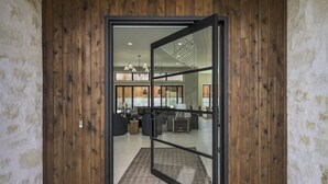 Ein modernes Interieur mit Holztür, Glastür und sichtbarem Wohnbereich mit Möbeln.