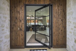 Um interior moderno com porta de madeira, porta deslizante de vidro e área de estar visível com móveis.