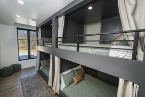 A modern interior with bunk beds, a large window, and a view of the outdoors. - Cedar Pointe Texoma Sleeps 18Swimming Pool (Kingston)