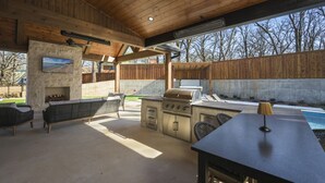 Eine Außenküche mit Grill, Sitzgelegenheit und Fernseher.