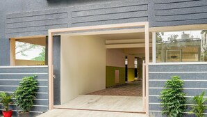 Une entrée moderne, avec un chemin d’accès dégagé menant à l’intérieur, des plantes en pot de chaque côté et un cadre de porte bien visible.