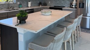 A modern kitchen with a large island, stainless steel appliances, and pendant lighting. - Ft. Myers Beach across street to Beach Golf Cart (Fort Meyers Beach)