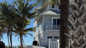 A beach pathway lined with palm trees leading to a white building with balconies. - Ft. Myers Beach across street to Beach Golf Cart (Fort Meyers Beach)