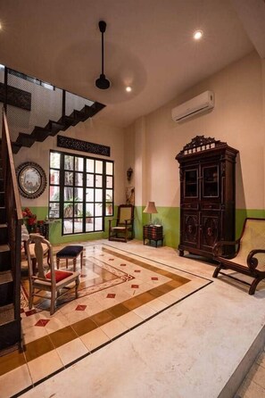 A room with a staircase, a large window, a cabinet, and a chair. - Casa Ambos Mundos en Merida Yucatan (Mérida)