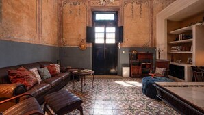 Ein Zimmer mit Ledersofa, einem gemusterten Boden, einer Chandelüster und einem Bücherregal.