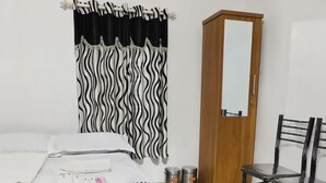 A bedroom with a bed, a chair, a wardrobe, a mirror, and a ceiling fan. - Kadingis homestay and eco tourism (Kadalundi)