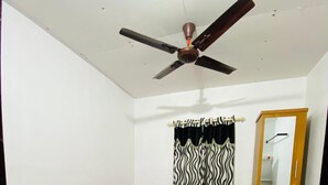 A bedroom with a single bed, a ceiling fan, a wardrobe, and a window with curtains. - Kadingis homestay and eco tourism (Kadalundi)