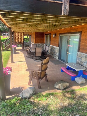 An outdoor patio area with a wooden pergola, stone walls, and a seating arrangement including a table and chairs. - Daggett Lake Cabin with Dock & Beach (Crosslake)