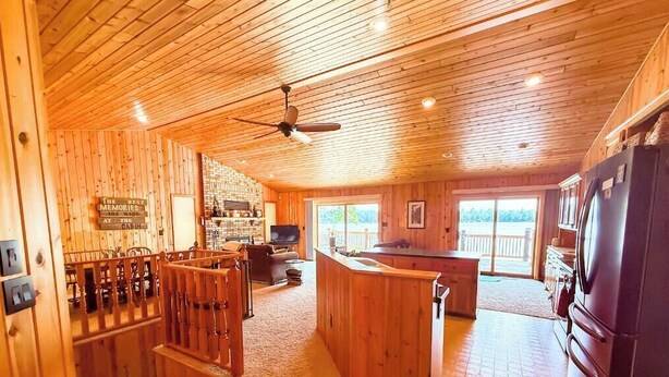 A cabin interior with wooden walls, a bar area, a kitchen, and a large window. - Daggett Lake Cabin with Dock & Beach (Crosslake)