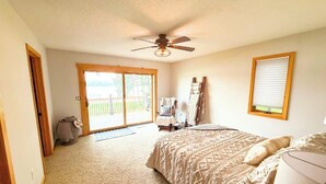 A bedroom with a bed, a ceiling fan, a window with blinds, and a view of a deck. - Daggett Lake Cabin with Dock & Beach (Crosslake)
