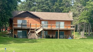 A two-story log cabin with a balcony, a staircase, and a covered outdoor area. - Daggett Lake Cabin with Dock & Beach (Crosslake)