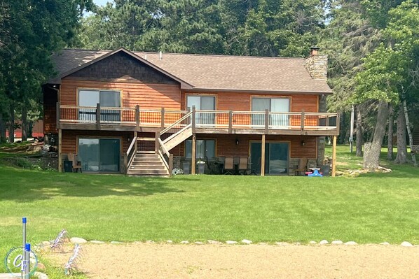 A two-story log cabin with a balcony, a staircase, and a covered outdoor area. - Daggett Lake Cabin with Dock & Beach (Crosslake)
