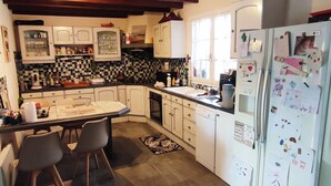 A kitchen with a dining table, chairs, a refrigerator, and cabinets. - House with swimming pool in the heart of the seaside resort of Ronce /La Tremblade (La Tremblade)