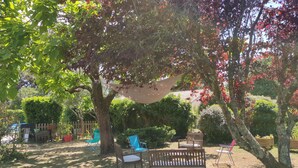 A garden with a bench, chairs, and a shaded area. - House with swimming pool in the heart of the seaside resort of Ronce /La Tremblade (La Tremblade)