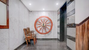 Un hall d’entrée en marbre, agrémenté d’une grande roue décorative, de chaises en bois et d’un escalier.