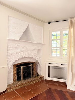A room with a fireplace, a radiator, and a window with curtains. - Large Villa with Pool and Private Tennis Court near Ormos Korthiou (Ormos Korthiou)