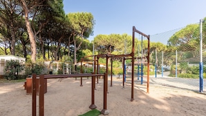 A playground with metal structures, a fenced area, and trees in the background. - Jesolo Family Resort (Jesolo)