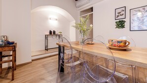 Een moderne keuken met een houten aanrecht, transparante stoelen en een vaas met bloemen.