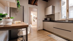 Een moderne keuken met houten vloeren, witte kastjes, een ingebouwde magnetron en een raam met uitzicht.