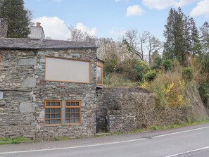 A stone building with a large window and a smaller window with a shutter. - Wilders Wood (Windermere)