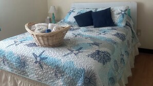 Una camera da letto con un letto, un cesto di asciugamani e quattro opere d'arte appese alle pareti.