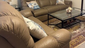 Un soggiorno con un divano in pelle marrone, un tavolino in vetro e un tappeto decorato.