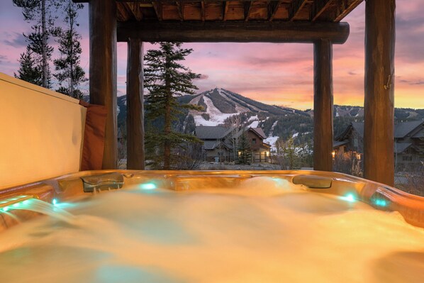 A hot tub with a view of a mountain at sunset.