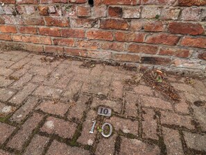 A brick wall with a metal plate marked '10' and a metal object on the ground. - 10 Church Walks (Chester)
