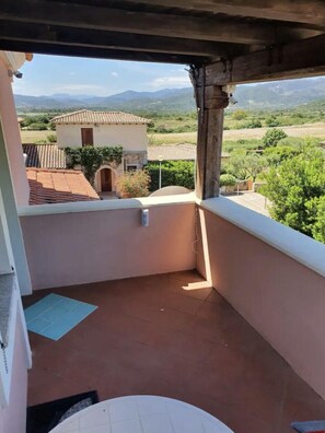 Ein Balkon mit Blick auf eine ländliche Landschaft, einem gefliesten Boden und einem kleinen Tisch.