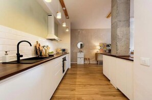 A modern kitchen with a wooden countertop, white cabinetry, and a central island.