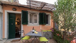 Eine Terrasse mit Tisch und Stühlen, einer Weinflasche und einer grünen Tür.