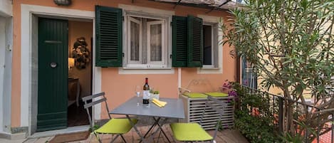 A patio with a table and chairs, a bottle of wine, and a green door.