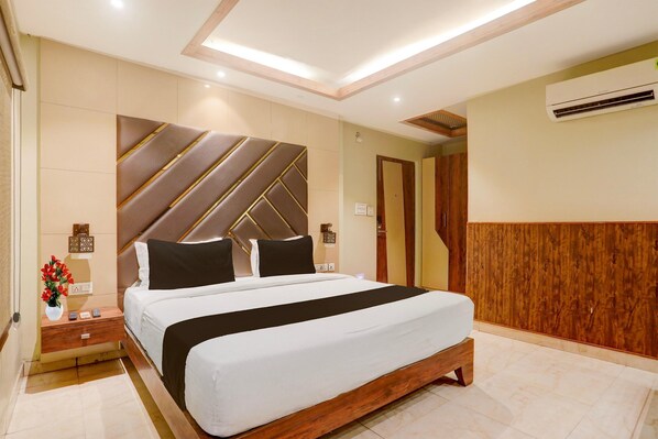 Une chambre d’hôtel moderne avec un grand lit, une tête de lit en bois et un système de climatisation intégré.