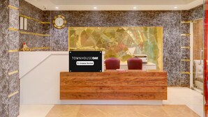 A reception desk with a sign reading 'Townhouse Oak,' a clock, and a geometric glass partition.