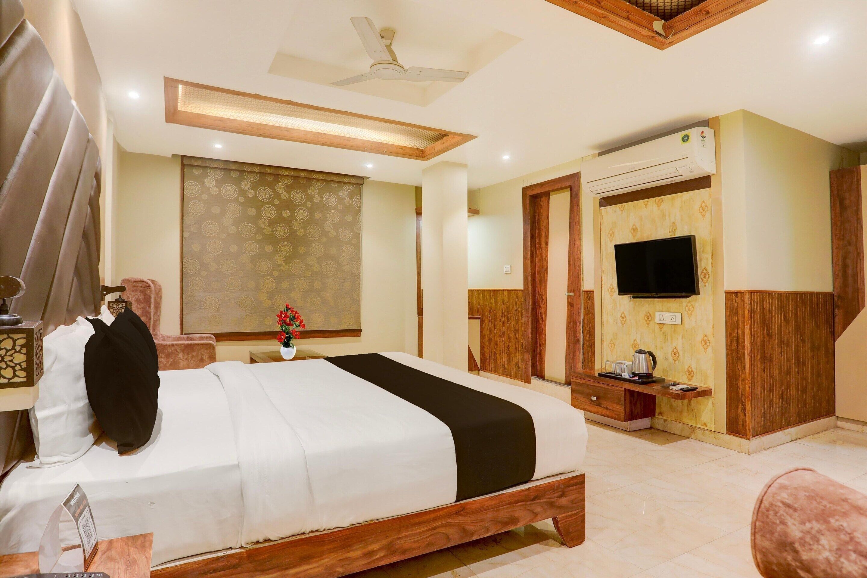 A hotel room with a bed, a TV, an air conditioner, and a wooden ceiling.