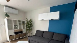 Una sala de estar moderna con un sofá gris, una mesa de centro blanca, un estante blanco y una pared azul de acento.