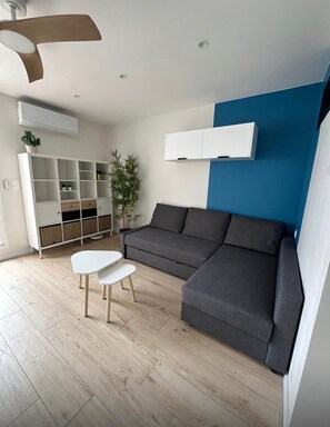 Ein modernes Wohnzimmer mit einem grauen Sofa, einem weißen Couchtisch, einer weißen Regaleinheit und einer blauen Akzentwand.