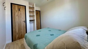 Un dormitorio con cama, ventilador de techo y armario con espejo.