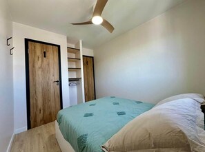 Ein Schlafzimmer mit Bett, Deckenventilator und einem Schrank mit Spiegel.