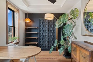 A room with a wooden table, a hanging light fixture, a potted plant, a dark door, and a mirror on the wall. - Trendy Fishtown | Spacious Backyard | Walk to Bars & Cafés (Philadelphia)