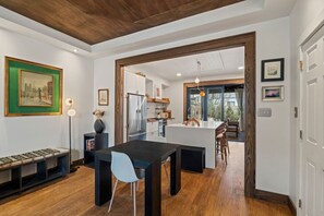 A modern kitchen with a central island, wooden flooring, and a dining area with a black table and white chairs. - Trendy Fishtown | Spacious Backyard | Walk to Bars & Cafés (Philadelphia)
