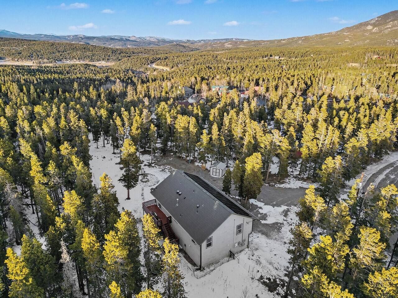 En bygning omgivet af skov med sne på jorden.