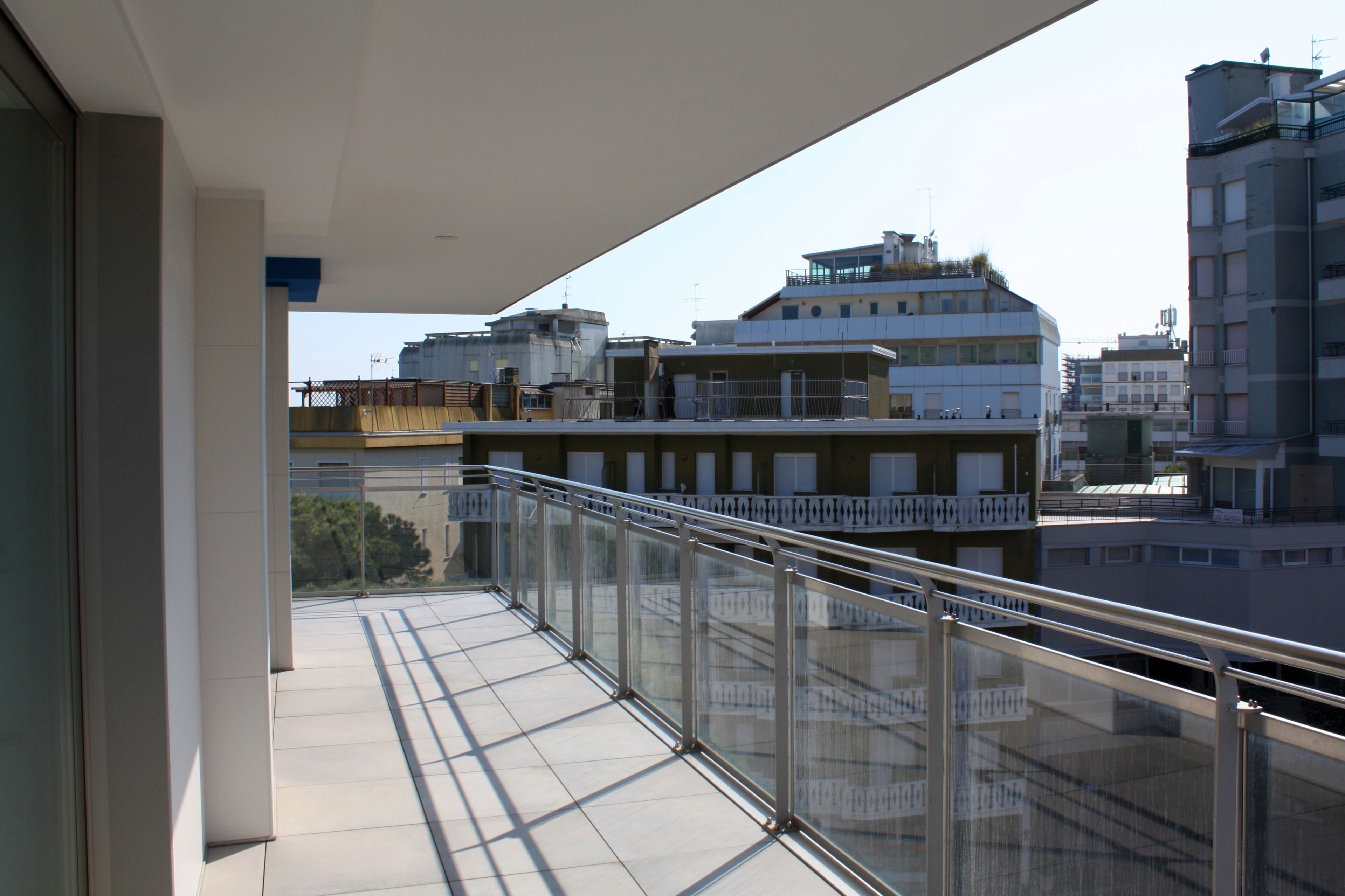 A balcony with a glass railing overlooking a cityscape.