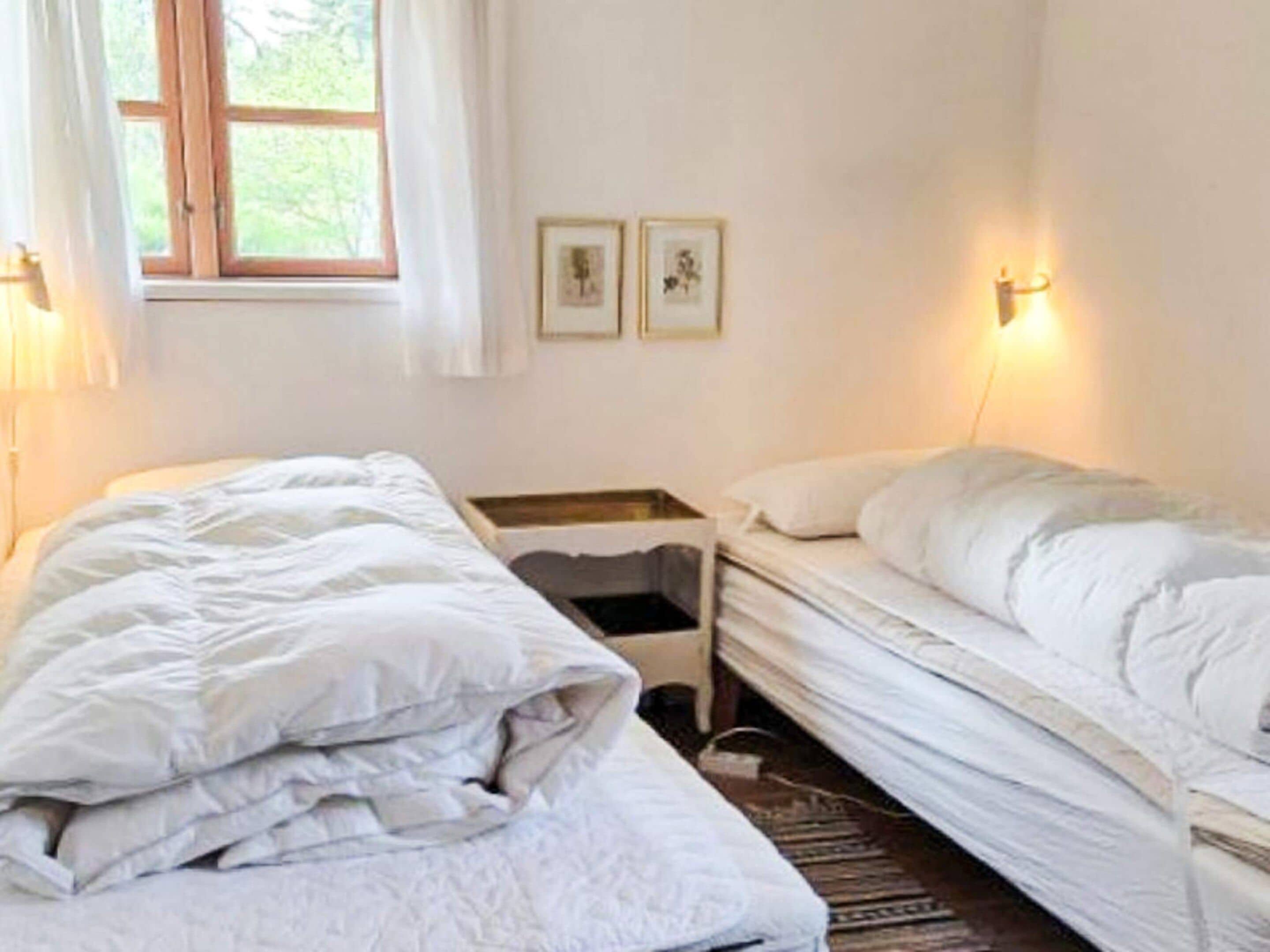 Een slaapkamer met twee bedden, een raam en wandlampen.
