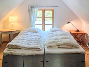 Ein Zimmer mit einem Bett, einem Fenster, einer Lampe und einem kleinen Tisch.