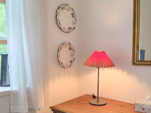 Een kamer met een houten tafel, een rode lamp en twee decoratieve borden aan de muur.
