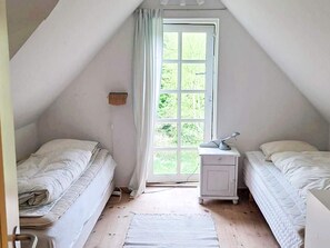 A small, single-room attic bedroom with two beds, a nightstand, and a window. - 6 Person Holiday Home in Frederiksvaerk (Frederiksvaerk)
