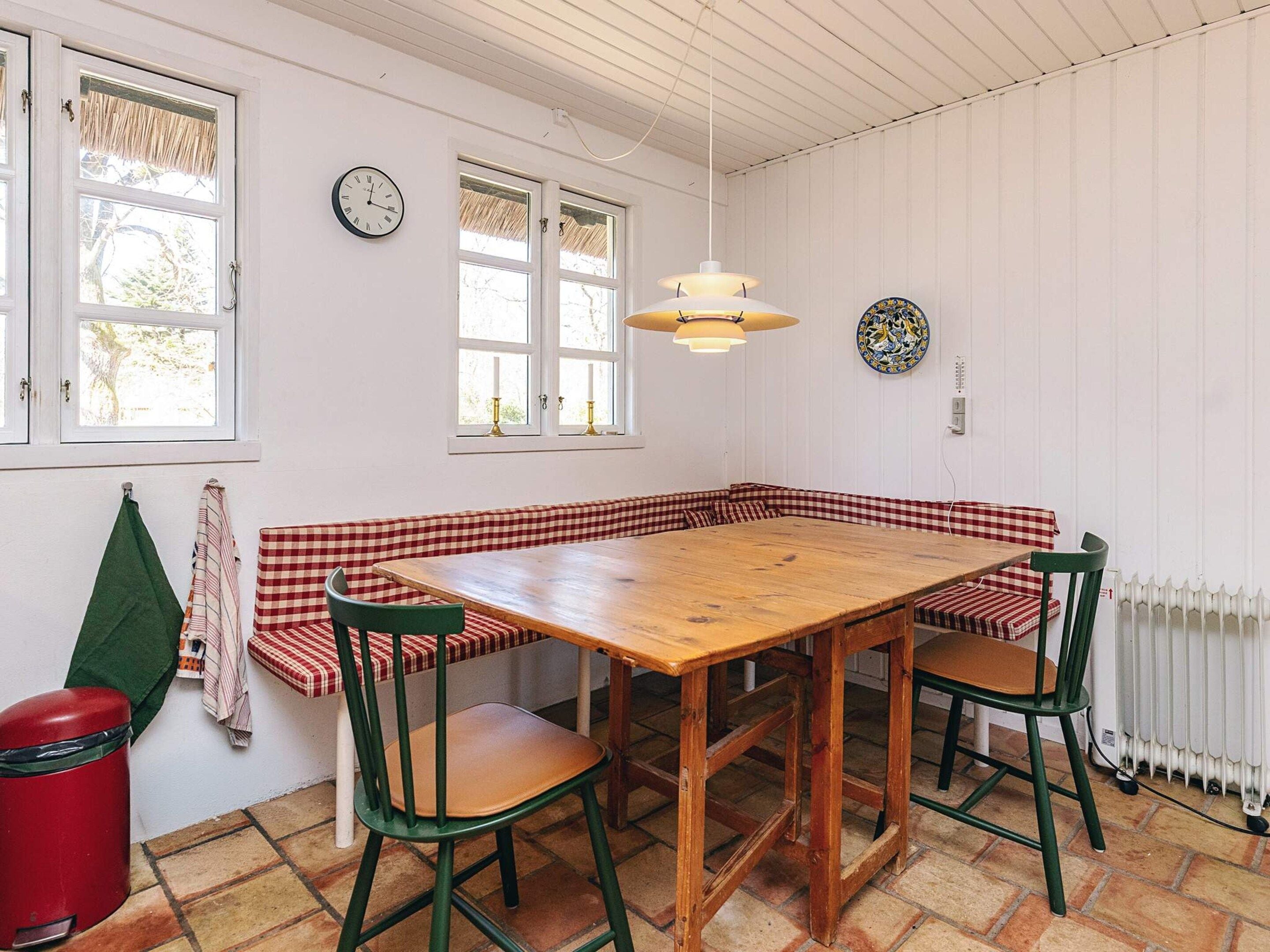 A dining area with a wooden table, checkered bench seating, and green chairs.