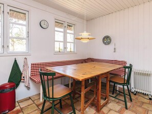 Ein Essbereich mit einem Holztisch, karierten Sitzbänken und grünen Stühlen.